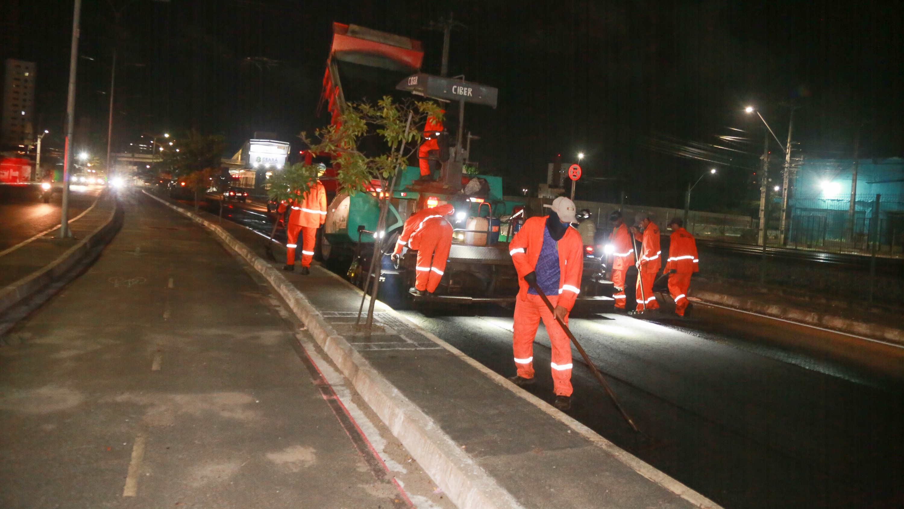 homens colocando asfalto em uma avenida à noite